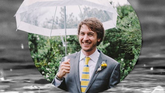 A man in a suit holds an umbrella over his head