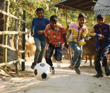 Young boys chase after a soccer ball