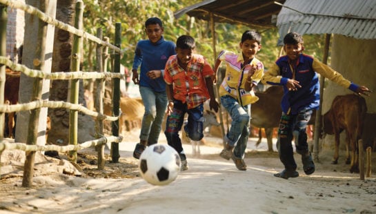 Young boys chase after a soccer ball