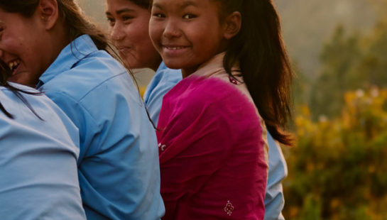 A photo of Sima and her three friends sitting on the edge of a short cliff