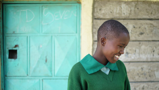 A girl in her school uniform smiles