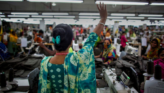 A woman in a garment factory holds her hand up