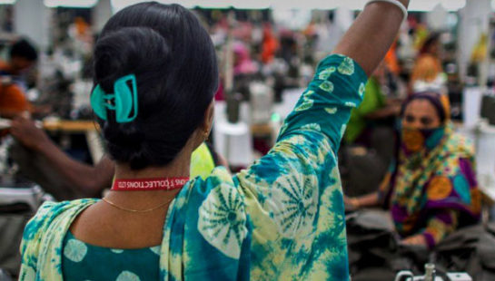 A woman in a garment factory holds her hand up