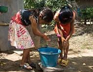 Two young girls wash their hands
