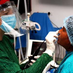 A doctor wears PPE while assessing a patient