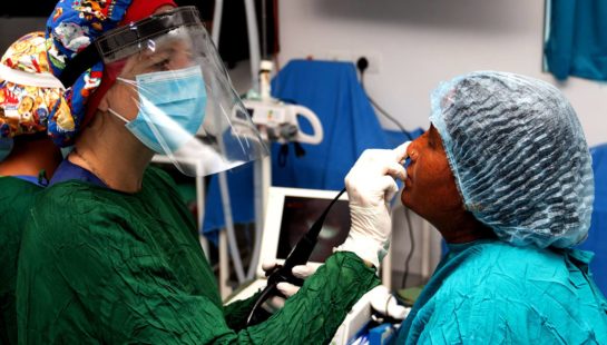 A doctor wears PPE while assessing a patient