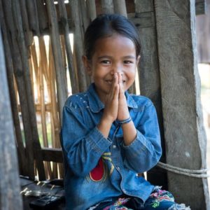 A young Cambodian girl holds her hands together in front of her face