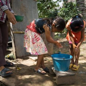Two Cambodian children wash their hands with a tippy tap