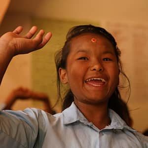 Sima, a Nepalese student, raises her hand while in class.