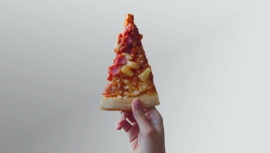A stock photo of a hand holding pizza