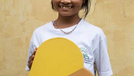 A young girl holding the Baptist World Aid heart