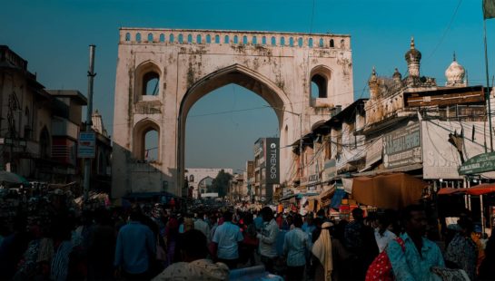 People standing near white concrete arch in a busy street