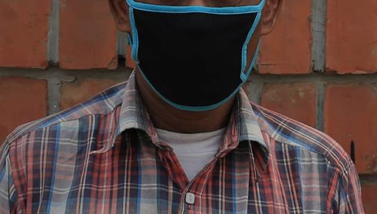 A garment worker stands in front of the factory where he works