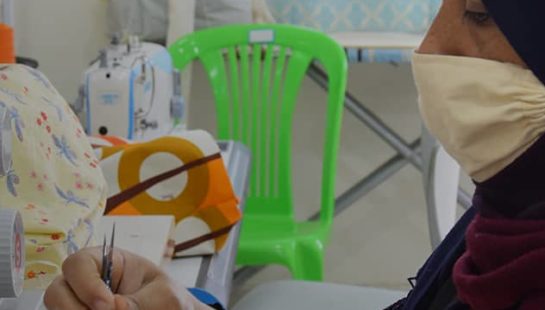 A woman in a sewing atalier crafts a cloth face mask.