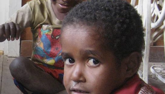 Children in Papua New Guinea sit on the floor reading.