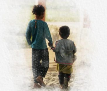 Two children walking hand in hand away from the camera
