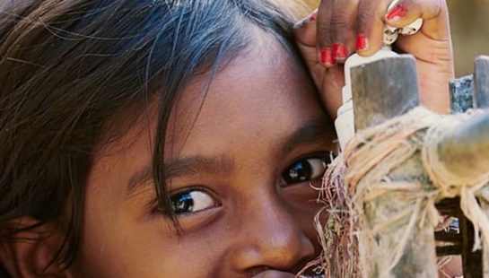 A small child sips directly from a running garden tap