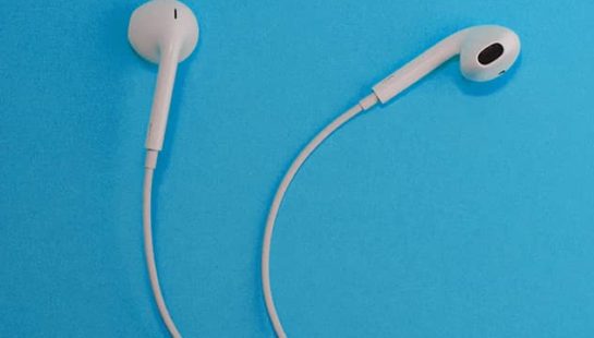 Two Apple earphones lying on a blue background