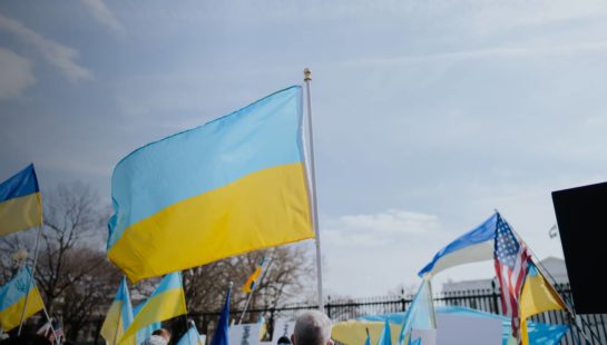 The Ukrainian flag is held up against the sky