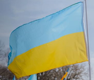 The Ukrainian flag is held up against the sky
