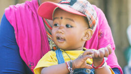 A young Nepalese baby in a yellow shirt and overalls