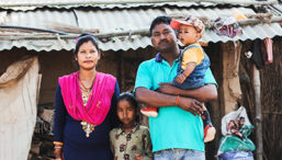 A Nepalese family stand together outside their home
