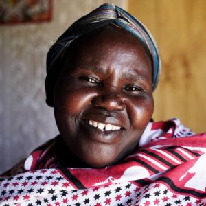 A Kenyan woman smiles to the camera in her home