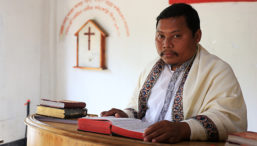 A man stands at a pulpit with his Bible open