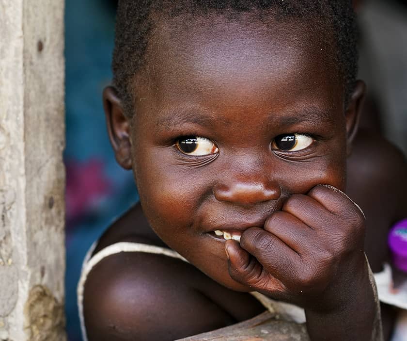 A young Ugandan girl looks out her family window