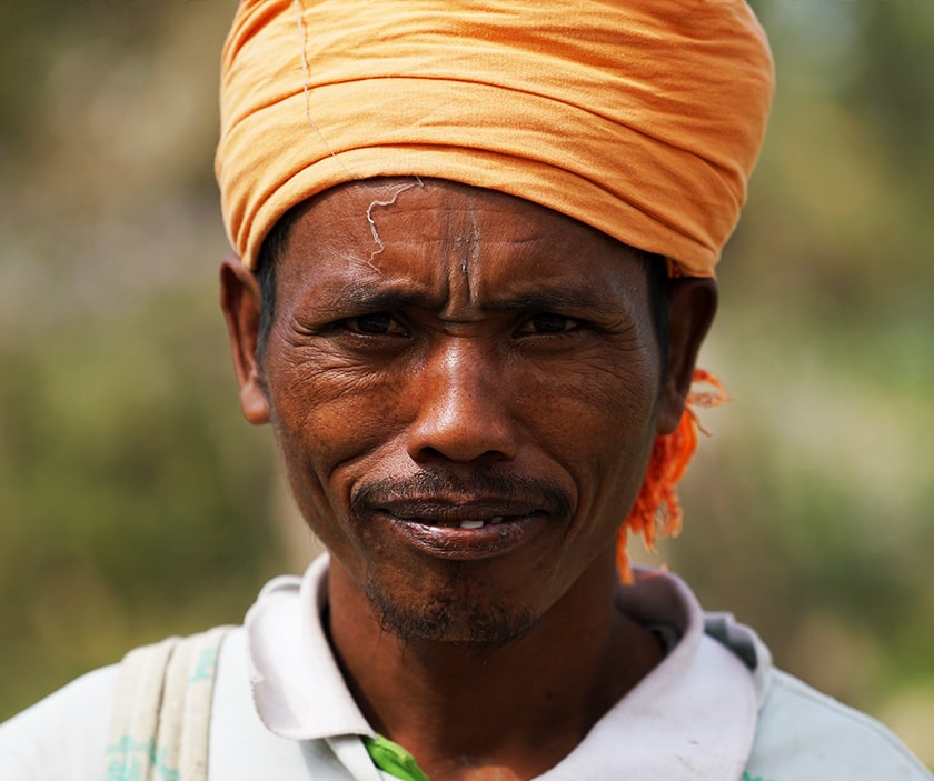 A man wearing an orange turban looks to the camera.