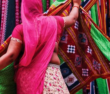 A woman in pink pulls at colourful fabric