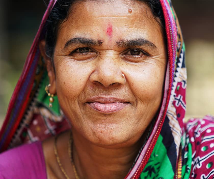 A Bangladashi woman in a colourful head scarf looks directly at the camera