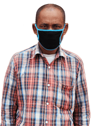 A garment worker stands in front of his factory, wearing a plaid shirt and black cloth mask