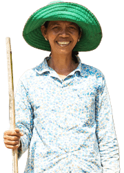 A Cambodian woman in a bright green sun hat holds a long cane in her right hand