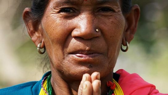 A woman with her palms together holds her hands up to her chin