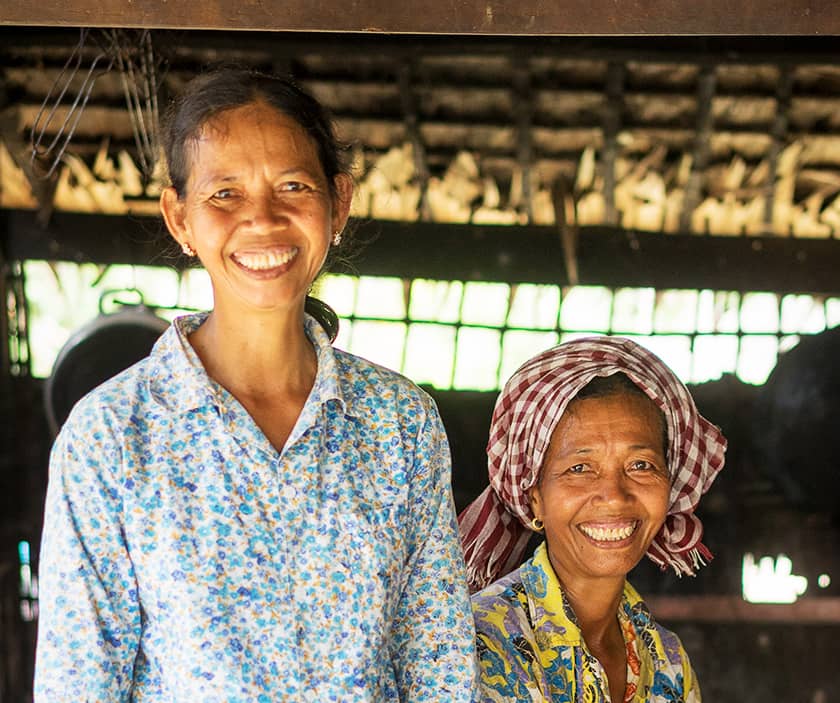 Two Cambodian women pose, one standing and one sitting