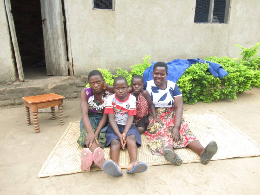Pacharo, a Malawi woman, sits with her three children outside