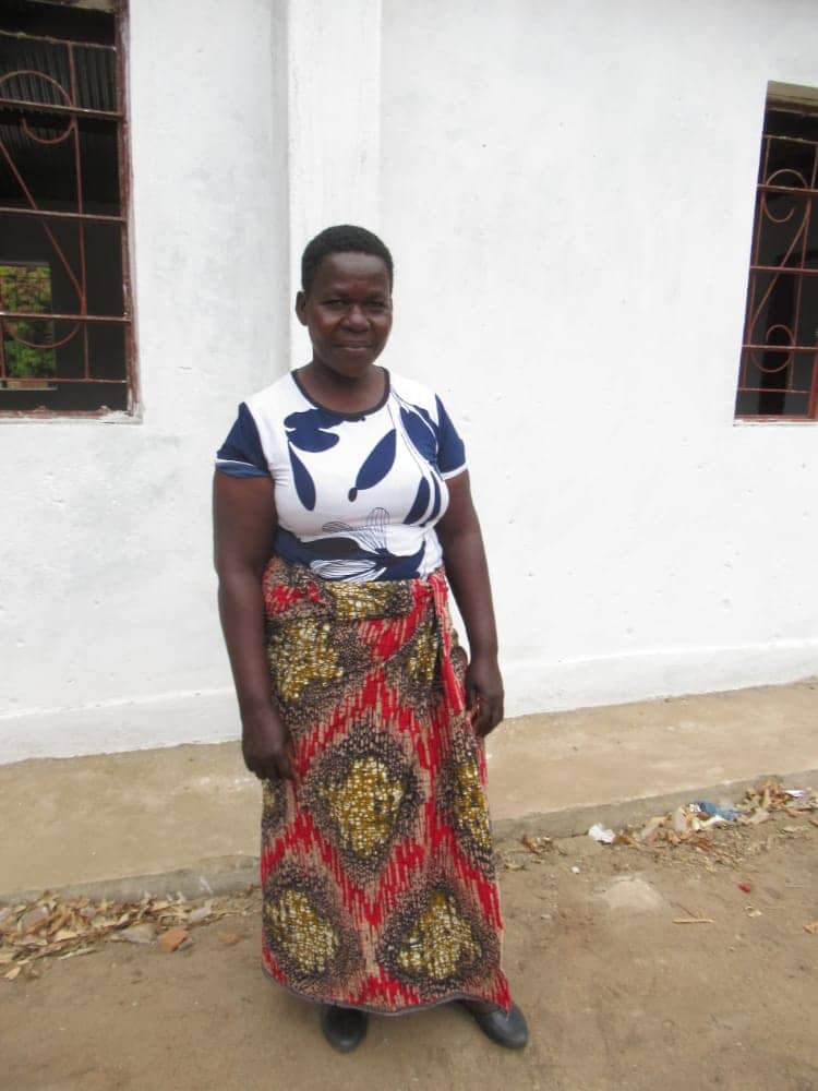 Pacharo, a woman from Malawi stands outside of a white building