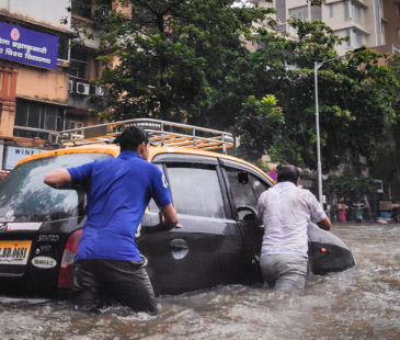 Two men push a car in flood waters
