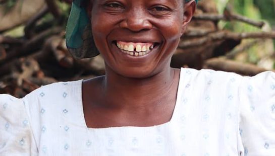 A Kenyan woman smiles and holds up her hands