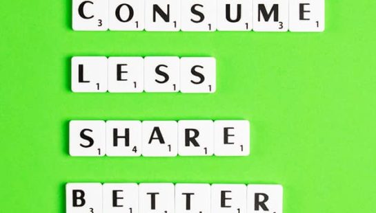 Scrabble letters on a neon green background which spell, 'Consume Less Share Better'