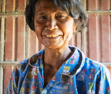 Woman in Cambodia wearing a blue shirt smiling at the camera