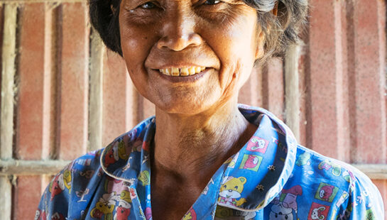 Woman in Cambodia wearing a blue shirt smiling at the camera