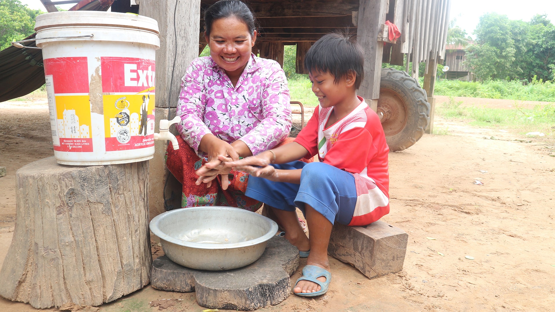 A woman teaches a young boy how to wash his hands