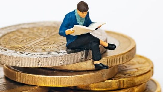 A small figurine sits on a stack of coins