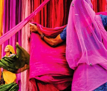Two women hold up colourful swaths of fabric