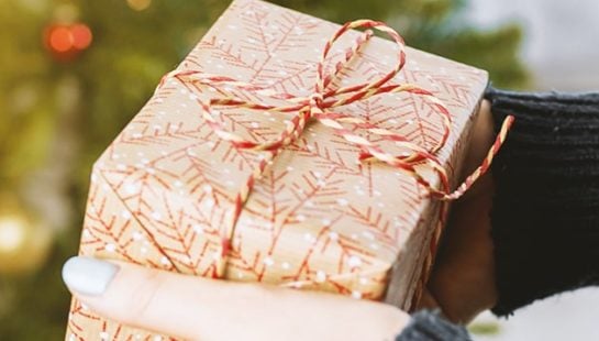 A woman holds a wrapped gift in hand