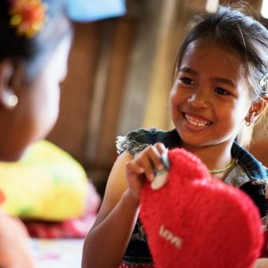 A young Cambodian girl plays with her sister