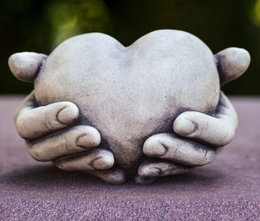 A stone sculpture of a heart in two hands