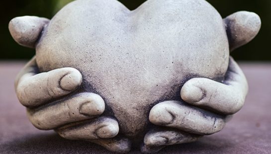A stone sculpture of a heart in two hands